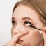 makeup artist applies mascara to lashes on a beautiful young woman blonde model, face make up