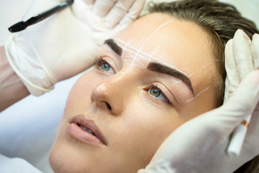 Woman during professional eyebrow mapping procedure
